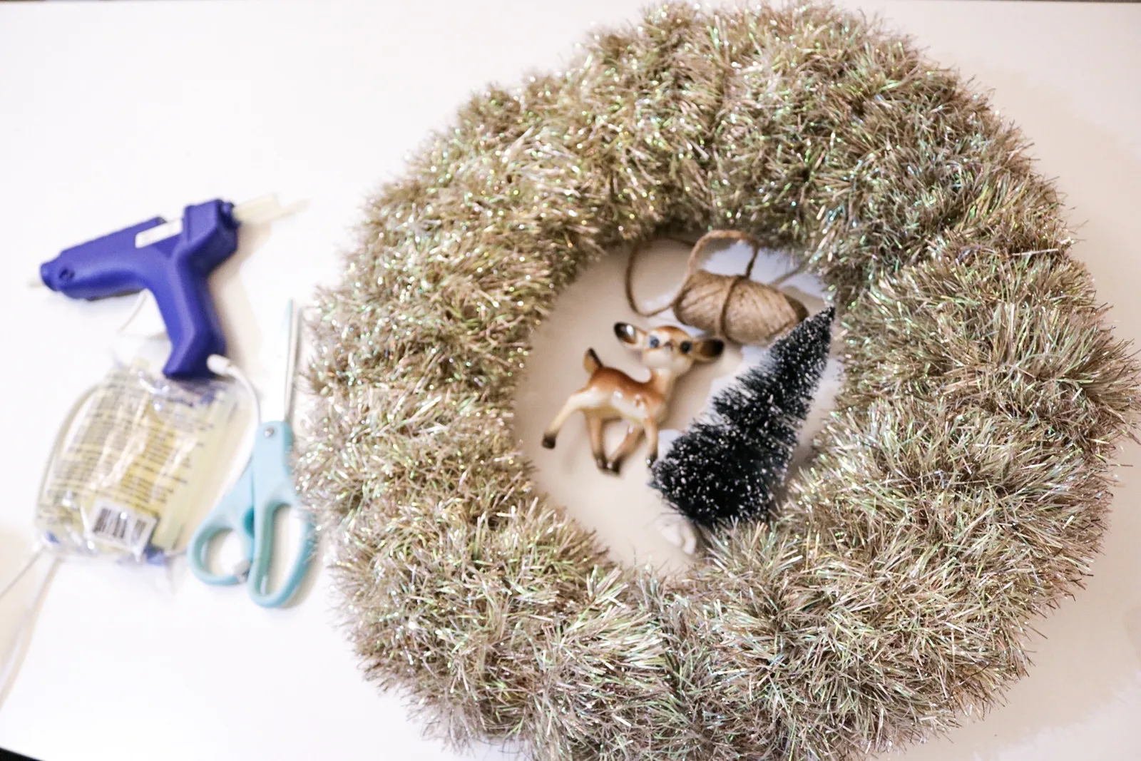 Mid century modern Christmas wreath made from tinsel garland with a vintage style deer, bottle brush tree and a bow