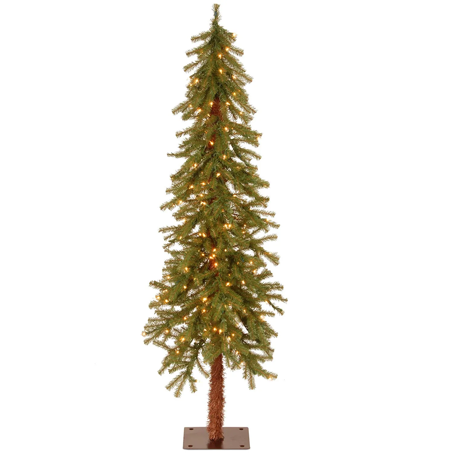 A slim pre-lit pencil Christmas tree tucked into a narrow corner of a small living room